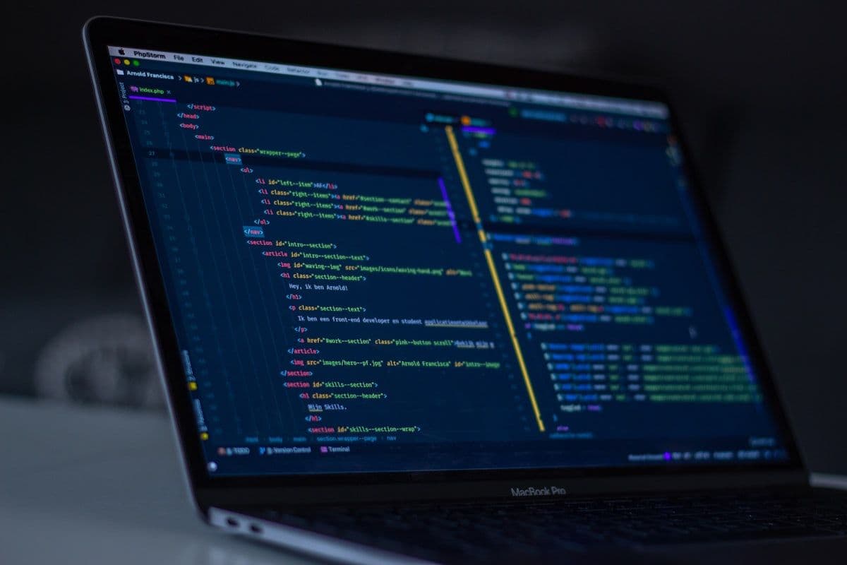 A developer's workspace with multiple monitors displaying colorful code, representing the intersection of AI-assisted vibe coding and professional software engineering